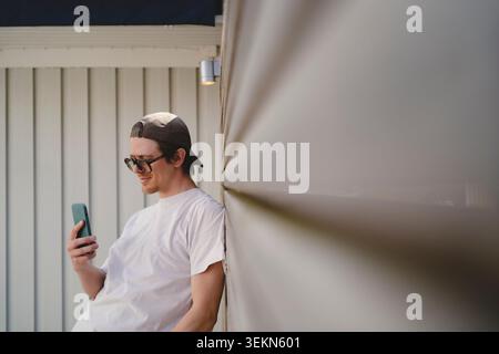 Uomo con occhiali da vista e berretto che scatta selfie tramite smartphone Foto Stock