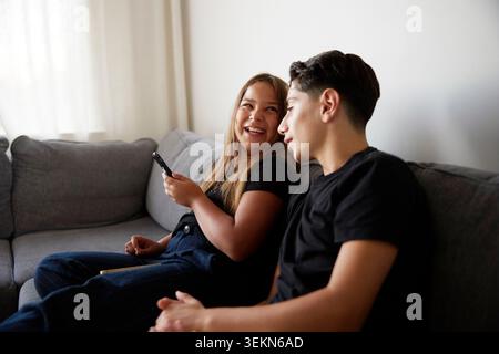 Fratello e sorella trascorrono del tempo libero sedendosi sul divano di casa Foto Stock