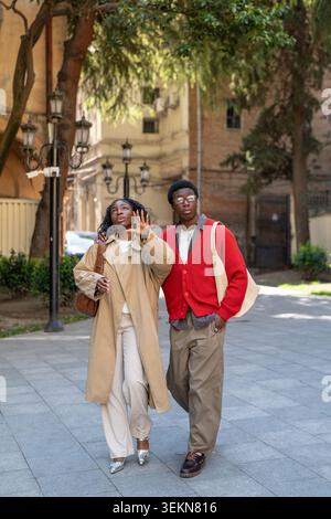 Uomo e donna afroamericani curiosi alla moda che passano il fine settimana a passeggiare in città insieme Foto Stock