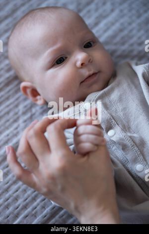 Neonato che tiene in mano il genitore che estrae e collega la mano Foto Stock