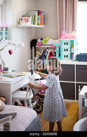 Vista dall'alto della ragazza in piedi vicino alla sedia nella camera da letto di casa Foto Stock