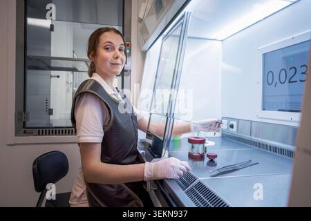 Ritratto di uno scienziato sorridente seduto vicino all'armadietto laminare del laboratorio Foto Stock