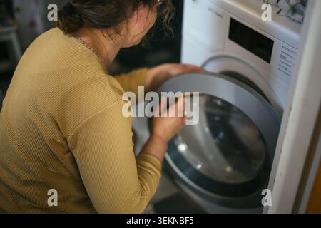 Vista ad angolo alto della donna che apre lo sportello della lavatrice Foto Stock