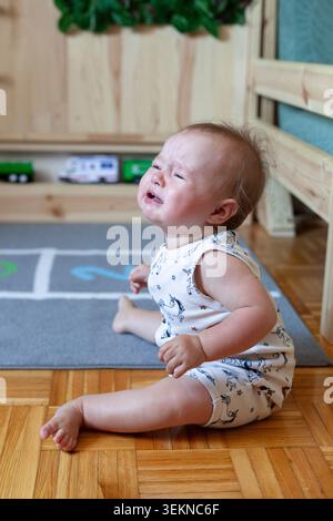 Baby sitter piangente sul pavimento di casa Foto Stock