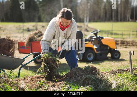 Donna che tira erbacce dal letto del giardino mentre lavora in fattoria Foto Stock