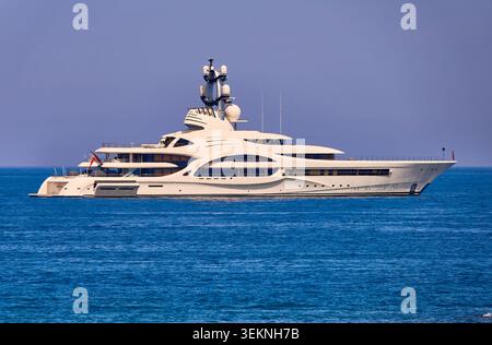 Superyacht bianco di lusso, Ambasciatore ad Anchor sul calmo mare blu sotto il cielo limpido vicino alla costa Foto Stock