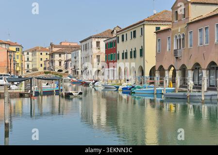 Edifici che costeggiano uno stretto canale con piccole barche da pesca ormeggiate nell'acqua di Chioggia Foto Stock