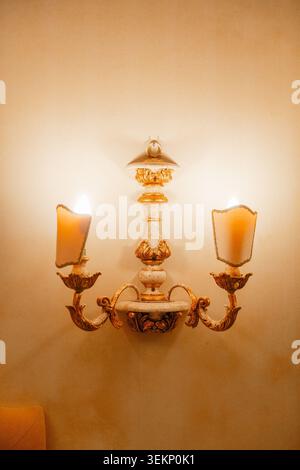 Applique decorativa in stile tradizionale che illumina le camere d'hotel. Concetto di comfort ed eleganti soluzioni di illuminazione. Foto Stock