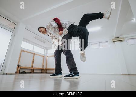 Due ballerini che eseguono un passaggio da partner durante le prove in uno studio di danza vuoto e luminoso Foto Stock