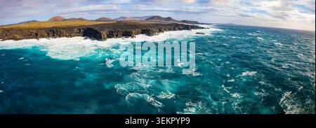 Scena aerea su El Golfo a Lanzarote che mostra una costa frastagliata, un terreno vulcanico e potenti onde oceaniche che si infrangono sulle rocce. Visualizza acquisizioni Foto Stock