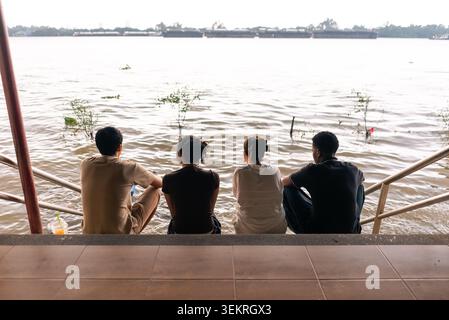Persone diverse sedute sul fiume, rilassandosi e godendosi il collegamento di gruppo all'aperto Foto Stock