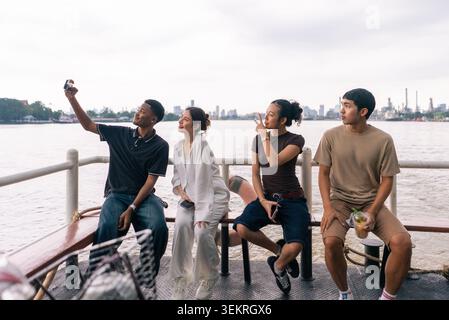 I giovani amici si divertono in barca sul fiume, catturando i ricordi con i selfie Foto Stock