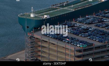 Nave cargo che scarica nuove auto in un parcheggio multipiano Foto Stock
