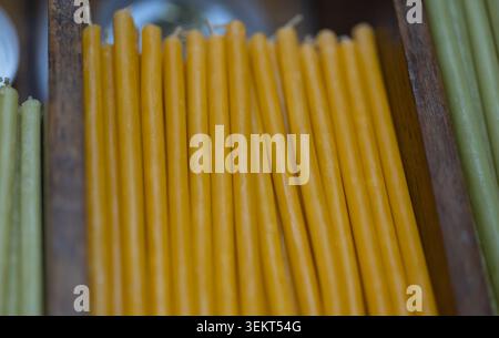 candele coniche di cera d'api naturali fatte a mano disposte in una scatola di legno rustica per la vendita in un mercato tradizionale. autentico prodotto ecologico dorato Foto Stock