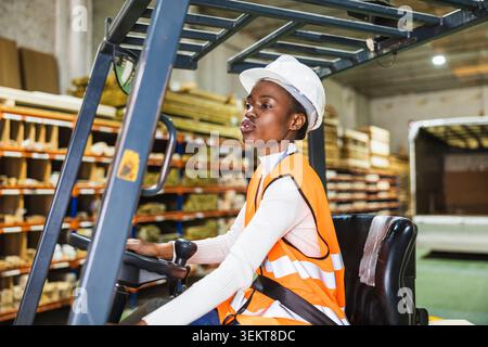 Lavoratrice industriale che guida un carrello elevatore in un boscaiolo Foto Stock