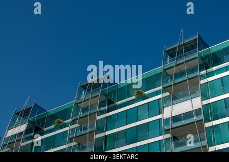 Vista ad angolo basso dell'innovativo Palazzo Mantegazza con facciata in vetro curvo e appartamenti di lusso a Paradiso, Lugano. Architettura in cristallo contemporanea con Foto Stock