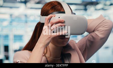 Tecnico donna in sala server che indossa occhiali VR per migliorare l'efficacia operativa dell'hardware. Esperto IT di data center che utilizza la tecnologia di realtà virtuale per monitorare i mainframe degli ingranaggi, telecamera B. Foto Stock