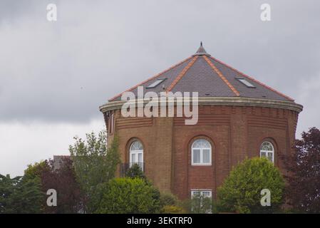 Foto ravvicinata della storica torre d'acqua ottagonale in mattoni rossi, con un tetto conico in ardesia in una giornata coperta Foto Stock