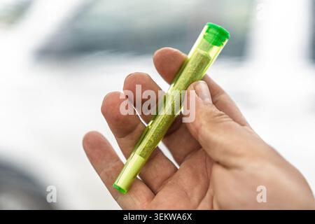 Pre-roll di marijuana in tubo trasparente tenuto in mano, concetto di uso ricreativo di cannabis Foto Stock