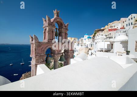 Vecchia Torre Campanaria della Chiesa Panagia Platsani con Case del Villaggio bianco e cupole Blu che si affacciano sulla Caldera del Mar Egeo, Oia e Santorini Foto Stock