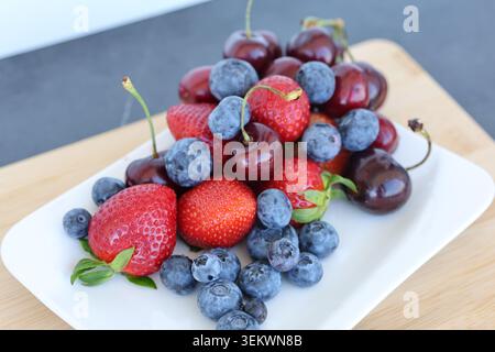 Fragole fresche assortite mirtilli e ciliegie su tavola bianca. stile di vita sano, nutrizione e concetti di pubblicità alimentare. Foto Stock