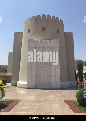 Vista frontale ad angolo basso di una maestosa torre storica in pietra arenaria araba con parapetti merlati e una grande porta in legno intagliato Foto Stock
