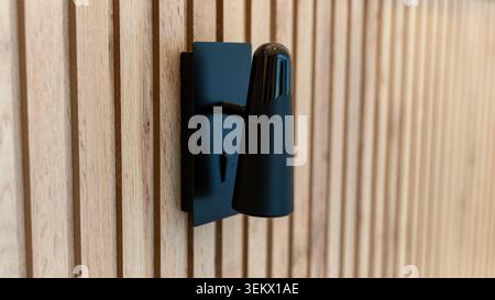 Moderna lampada da parete nera su pareti interne in legno Foto Stock