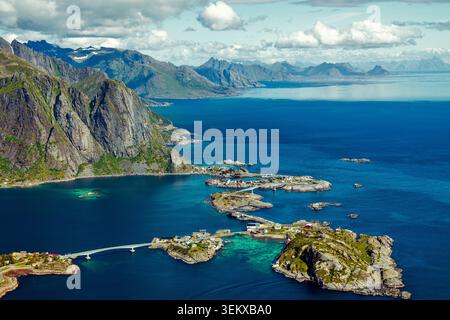 Reine, Norvegia - 13.07.2020: Paesaggio mozzafiato di ripide cime di granito e villaggi costieri tra profonde acque blu e luce solare estiva Foto Stock