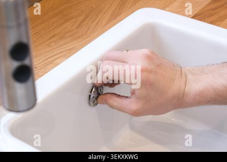 Tappo di scarico lavello a regolazione manuale in lavabo in ceramica bianca Foto Stock