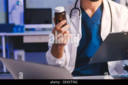 Uomo, medico e computer portatile che scrivono nella ricerca sanitaria, nelle comunicazioni o nei social media alla scrivania dell'ufficio. Maschio medico esperto che lavora sul computer in linea Foto Stock