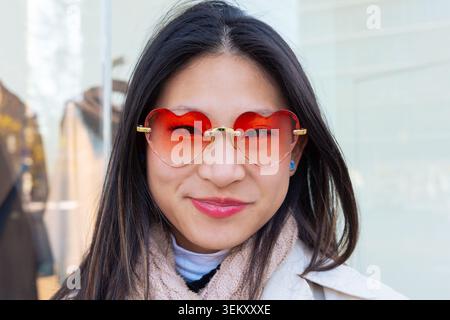 Ritratto ravvicinato di una donna asiatica felice che indossa eleganti occhiali rossi a forma di cuore Foto Stock