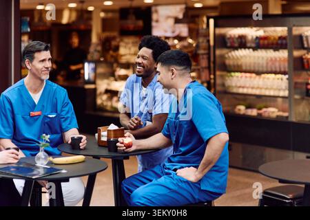 Personale medico maschile felice che si gode una pausa caffè nella caffetteria Foto Stock