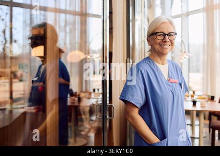 Ritratto di donna anziana sorridente in piedi con la mano in tasca Foto Stock