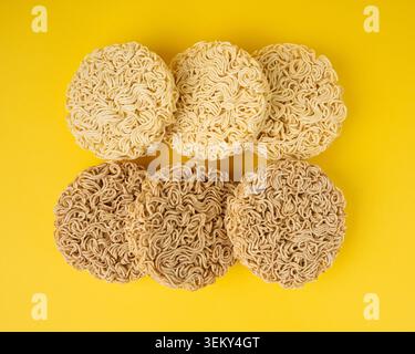 Tagliatelle crude, set di 6 tagliatelle Ramen rotonde asciutte, Vermicelli coreani crudi, pasta rapida di segale cinese e grano, maccheroni istantanei su sfondo giallo Vista dall'alto Foto Stock