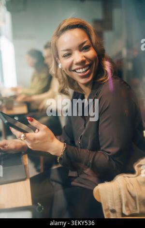 Donna d'affari felice che ha uno smartphone e guarda un collega Foto Stock