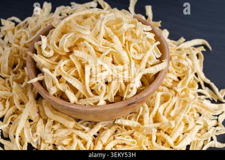 Pasta spatzle Passatelli in ciotola, spaghetti di spaetzle crudi, maccheroni tedeschi fatti in casa secchi, pasta all'uovo di spaetzle sveva su sfondo nero Foto Stock