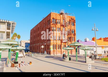 Venice Beach, California - 8 gennaio 2026: Un edificio a più piani in mattoni rossi si erge lungo la passerella di Venice Beach sotto un cielo azzurro e limpido, caratterizzato da Foto Stock