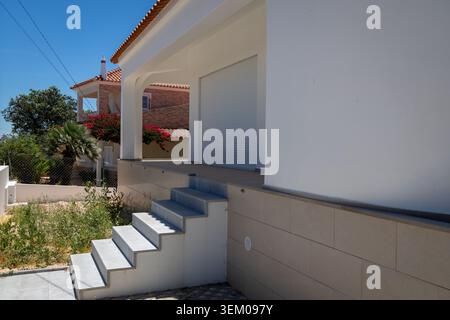 Monte Canelas Algarve Portugal, Un edificio residenziale contemporaneo caratterizzato da un esterno bianco pulito, una base piastrellata testurizzata e una scalinata in cemento l Foto Stock