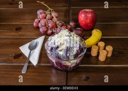 STILL Life presenta una ciotola di acai servita con frutta come uva, mela, banana su sfondo di legno. Concentrati su colori vivaci, texture uniformi e marcature Foto Stock
