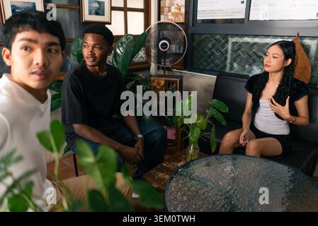 Diversi giovani adulti che conversano in modo informale al moderno Cafe' Foto Stock