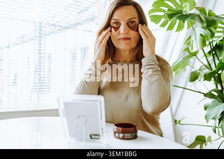 donna di mezza età con lunghi capelli biondi e macchie sotto gli occhi Foto Stock