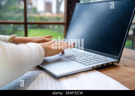 Vista ravvicinata delle mani che gestiscono un notebook in uno spazio di lavoro moderno. Adatto per concetti relativi al lavoro in remoto, al business online, alla produttività digitale, Foto Stock