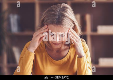 Donna che soffre di stress e ansia, che tiene capo in ufficio, concetto di salute mentale Foto Stock