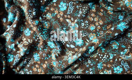 Sfondo fotografico in tessuto stampato. Si piega caotica in luoghi diversi. Ornamento fatto di diversi fiori e foglie. Blu, marrone, arancione. Foto Stock