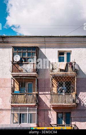 Balconi di appartamenti erosi con bucato e una parabola satellitare su un edificio in stile sovietico a Ulan Bator, Mongolia. Foto Stock