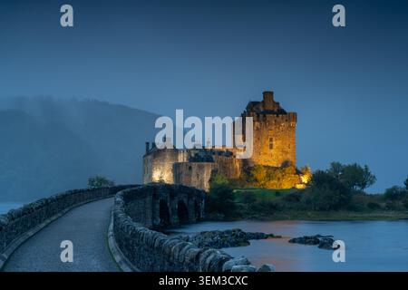 Castello di Eilean Donan al crepuscolo, Dornie, Highland, Scozia, con luce serale, riflessioni e un suggestivo paesaggio delle Highlands scozzesi. Foto Stock