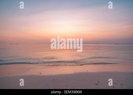 Tramonto pastello morbido su un mare tropicale calmo con cielo lilla-mauve e riva gentile. Bagliore oceanico sognante. Spazio di copia per il benessere dei viaggi estivi Foto Stock