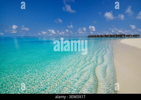 Lago tropicale turchese con bungalow di lusso sull'acqua e banchina di sabbia bianca. Oceano blu cristallino. Paradiso di vacanza per il benessere e il relax Foto Stock