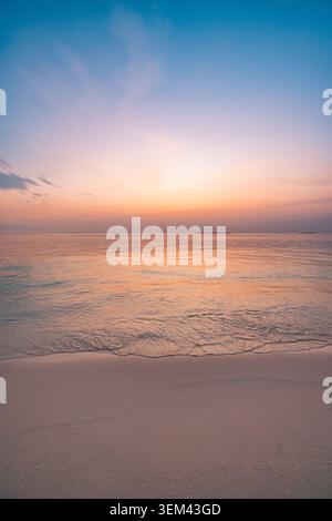 Cielo pastello rosa attutito all'alba su un mare tropicale calmo e minimale. Acqua liscia come il vetro, orizzonte morbido. Sfondo di benessere per la meditazione pacifica con spazio per il testo Foto Stock