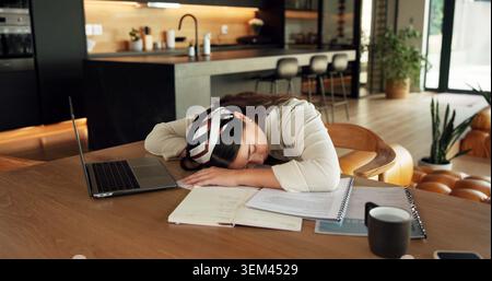 Lavoratore libero, addormentato e donna con un notebook a casa, sovraccarico di lavoro o stanco di scadenze di progettazione sulla scrivania. Grafico, burnout e persona con Foto Stock